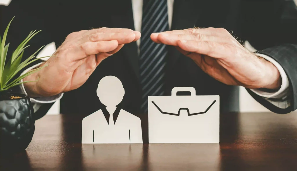 Hands protectively hovering over a professional figure and briefcase, symbolizing Professional Indemnity Insurance coverage.