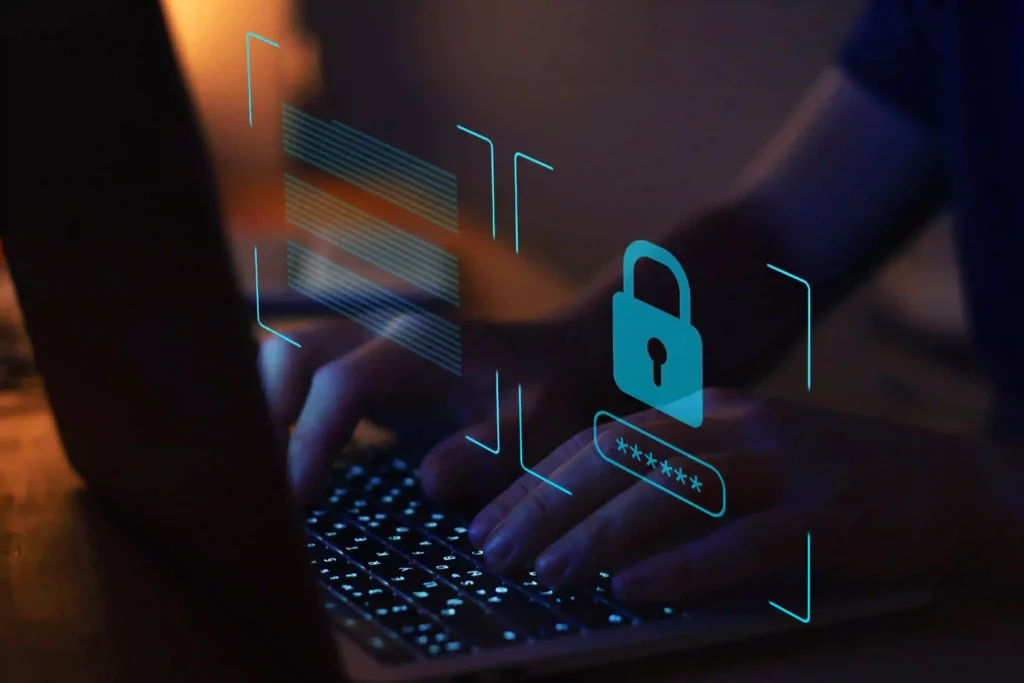 Hands typing on a laptop keyboard with a digital lock icon overlay, symbolising cyber protection insurance.